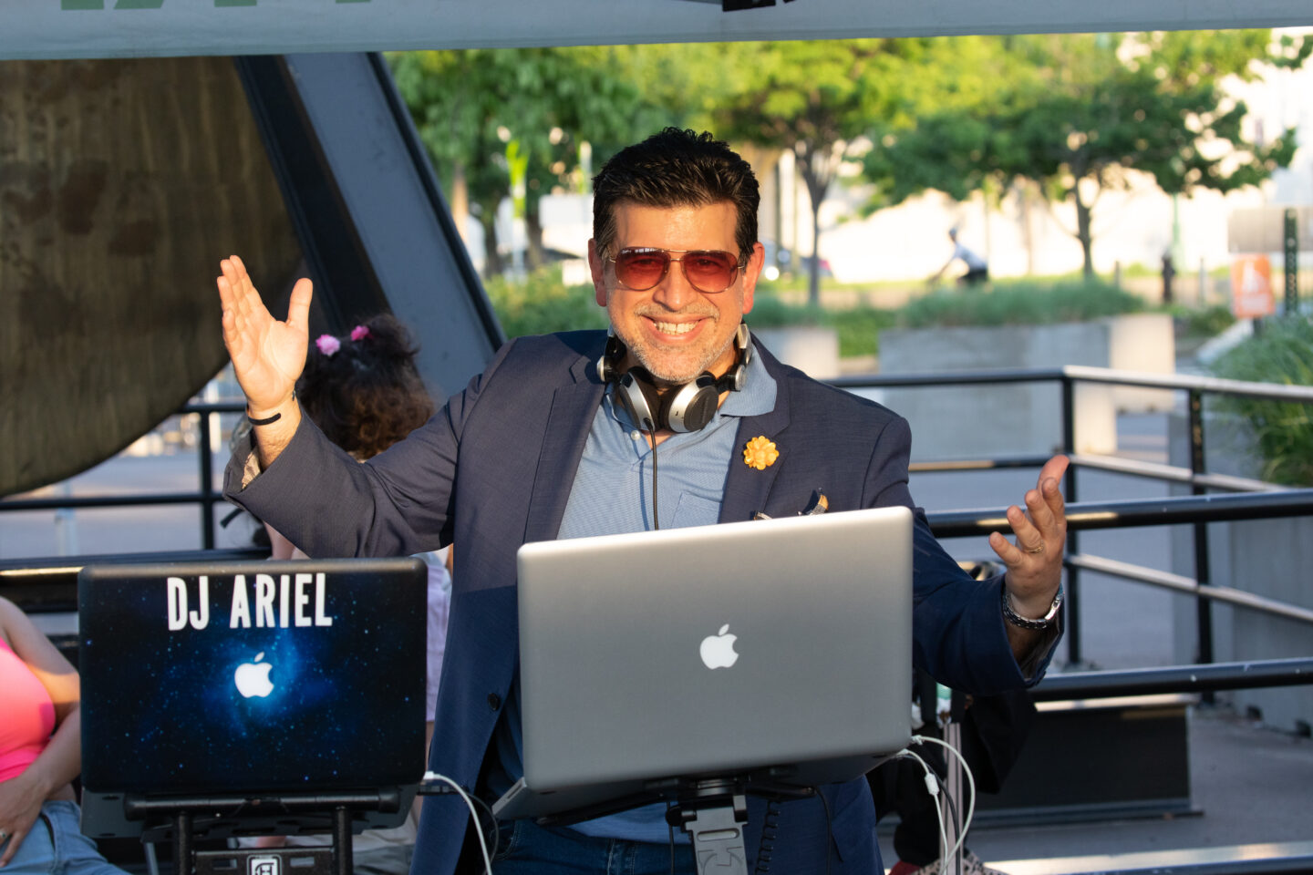 DJ Ariel smiles behind laptop at Pier 76 for Sunset Salsa